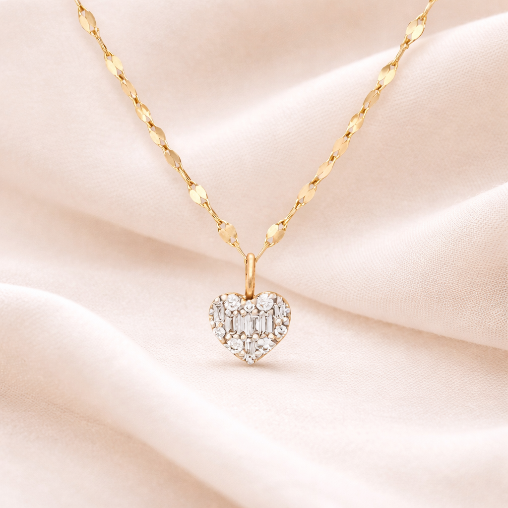 Gold necklace with a heart-shaped diamond pendant on a soft pink fabric background