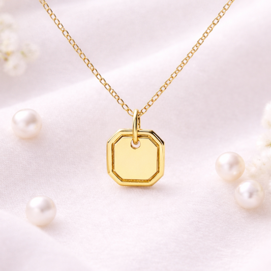 Gold necklace with a hexagonal pendant on a light background