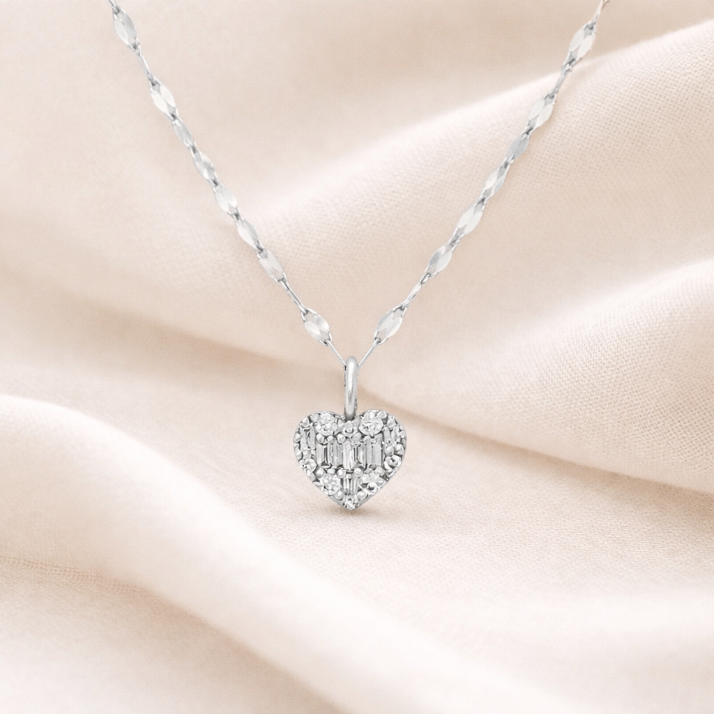 Silver heart-shaped pendant necklace on a soft pink fabric background