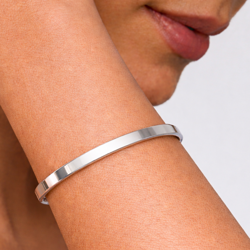 Silver bracelet on a person's wrist with a neutral background
